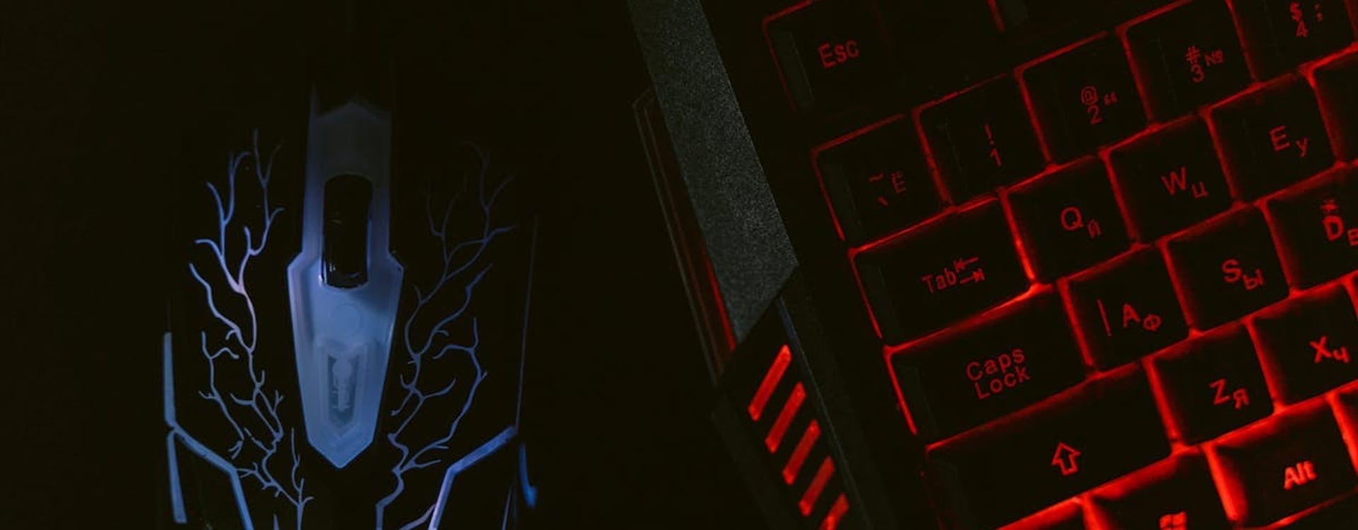 Close-up of a glowing gaming mouse and a backlit keyboard in a dim setting, showcasing a tech-savvy setup.