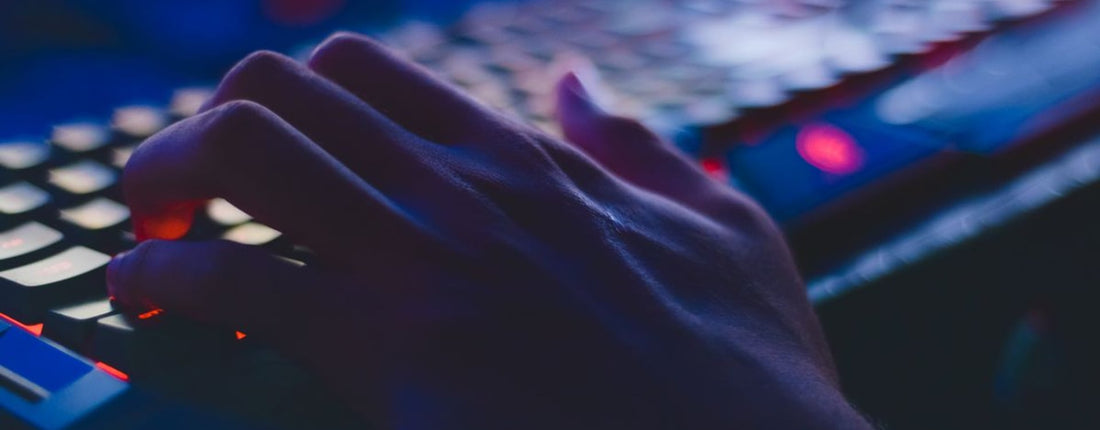 A hand typing on a glowing keyboard in dim lighting, perfect for tech themes.