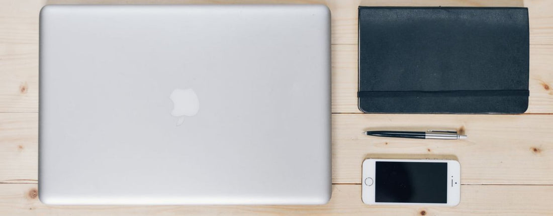 A clean, organized desk featuring a laptop, smartphone, notebook, and pen, ideal for productivity.