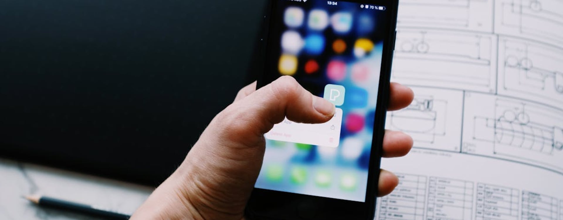 An iPhone resting on a bedside table at night, subtly warm, indicating active background processes like Photos indexing.
