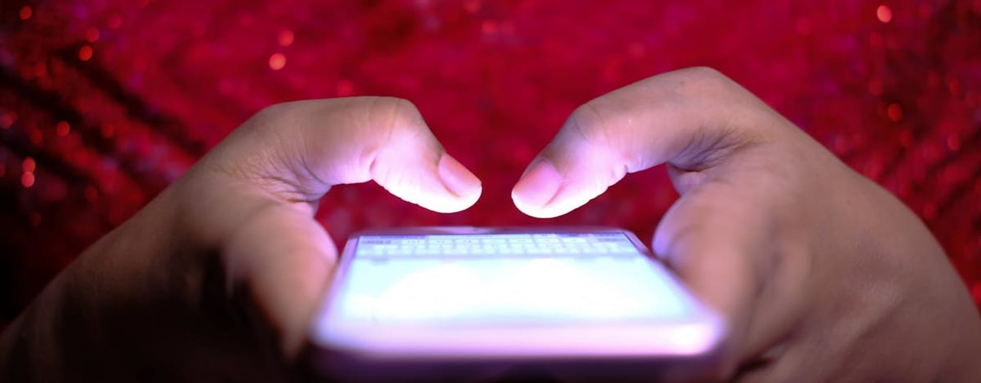 A person using a smartphone outdoors in bright sunlight, struggling with phone heat during a demanding task.