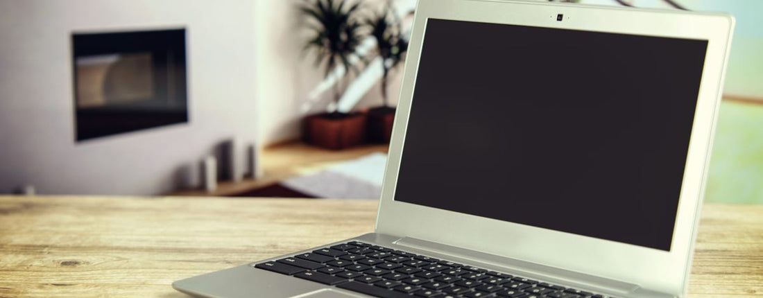 Sleek laptop on a wooden desk with blurred contemporary home interior in the background.