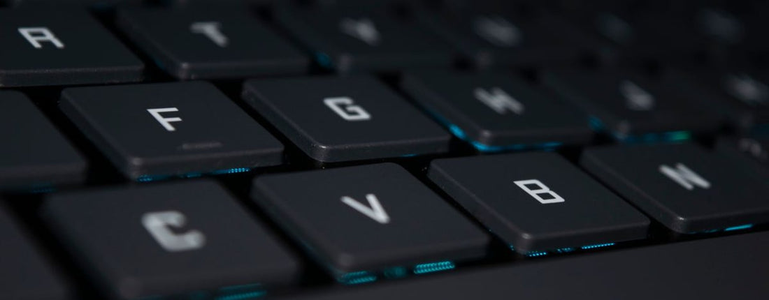 Detailed view of a black laptop keyboard with blue backlighting, showcasing modern technology.