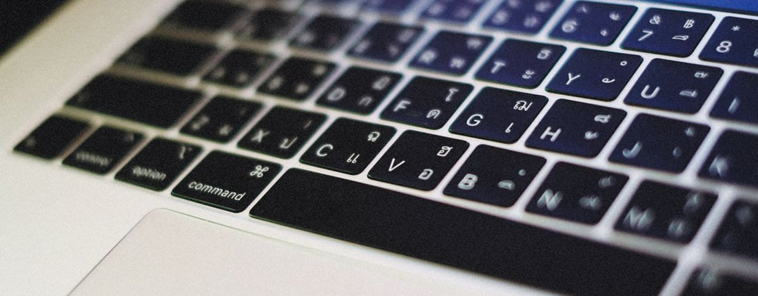 Closed MacBook-style laptop on a desk, illustrating the underside clearance to check before buying a cooling stand