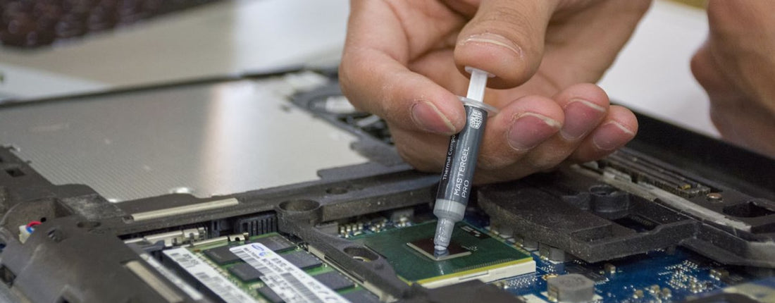 Close-up of hand applying thermal paste to a laptop microchip for maintenance.