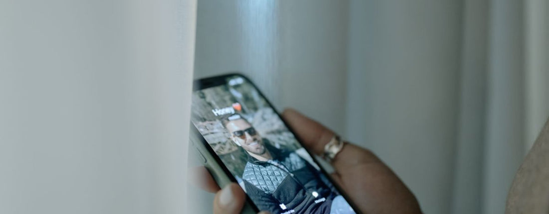 A hand holding a smartphone showing an incoming call notification with a photo of a man on the screen.