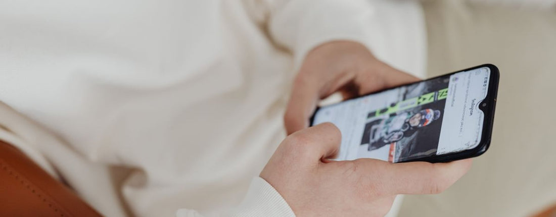A close-up view of hands holding a smartphone displaying a sports image indoors.