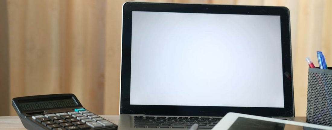 Organized office desk with a laptop, calculator, and tablet ready for business tasks.