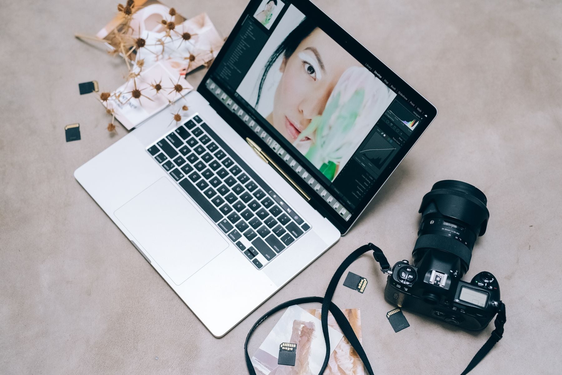 A MacBook showing a photo editing workflow beside a camera